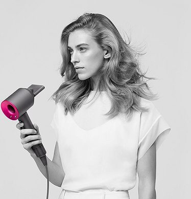 Девушка блондинка держит в руках фен